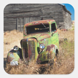Rusting car in front of abandoned farm square sticker