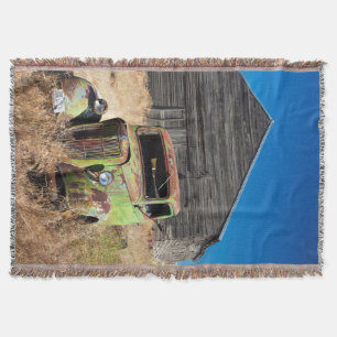 Rusting car in front of abandoned farm throw blanket