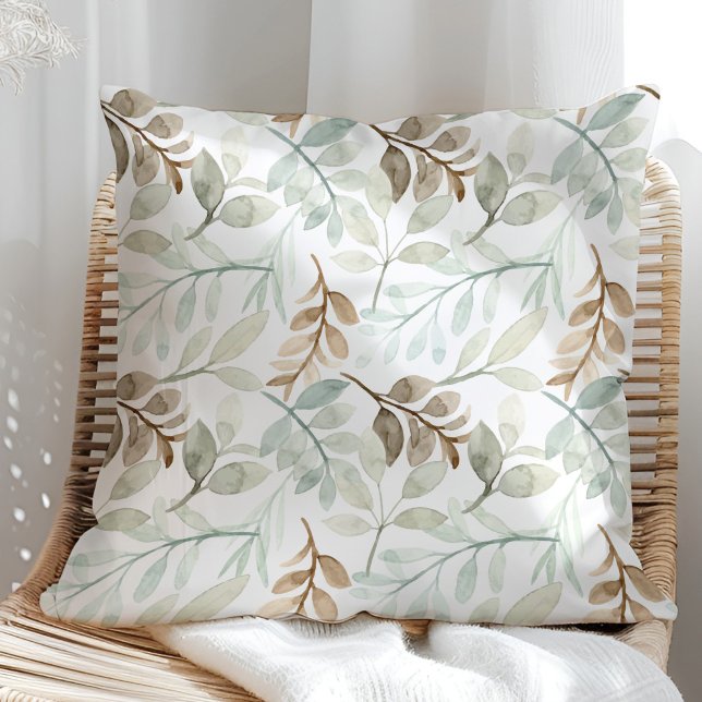 Sage Green and Brown Watercolor Leaves Cushion (Sage Green and brown watercolor leaves on a white throw pillow in a rattan armchair.)