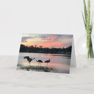 Sandhill cranes silhouette at sunset at the lake holiday card