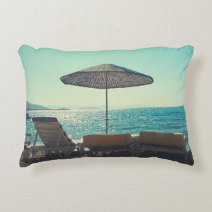Sandy beach on a sunny afternoon, with parasols a decorative cushion