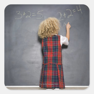 School girl (6-7) writing on blackboard, square sticker