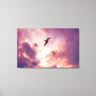 Seagulls flying in a sunset sky canvas print