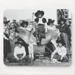 Seven rodeo cowgirls jokingly posing with a donkey mouse mat
