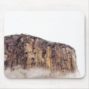 Sheer cliff rising above clouds mouse mat