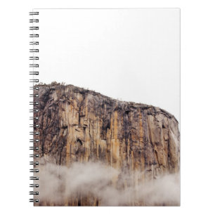 Sheer cliff rising above clouds notebook