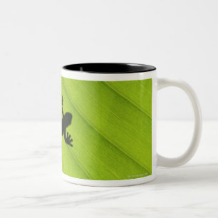 Silhouette of frog through banana leaf Two-Tone coffee mug
