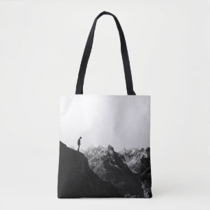 SILHOUETTE OF PERSON STANDING ON CLIFF IN FRONT OF TOTE BAG