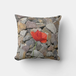 Single red poppy flower on small grey stones cushion