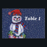 Smiling Snowman Holding String of Christmas Lights Table Number<br><div class="desc">This table number card for your parties or events has a smiling snowman with a carrot nose wearing a winter blue and red hat and scarf holding a lit string of colourful Christmas lights on a dark blue background with falling snow.  Customise your table number with the template.</div>