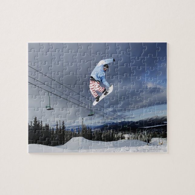 Snowboarder jumping in mid-air doing a backside jigsaw puzzle (Horizontal)