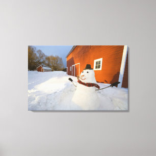 Snowman in front of red barn in Columbia Falls Canvas Print