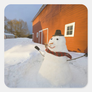 Snowman in front of red barn in Columbia Falls Square Sticker