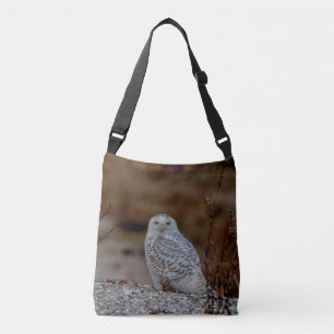 Snowy owl sitting on a rock crossbody bag