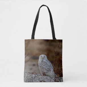 Snowy owl sitting on a rock tote bag