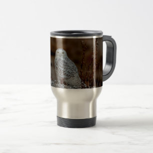 Snowy owl sitting on a rock travel mug
