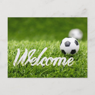 Soccer ball on green grass with welcome sign postcard
