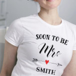 Soon to be Mrs. personalised name T-Shirt<br><div class="desc">Soon to be Mrs. personalised with name for the bride to be. Soon to be in black uppercase letters with Mrs in tall decorative cursive lettering. Embellished with a black doodle arrow and red heart. Personalise with new surname in matching black font.</div>