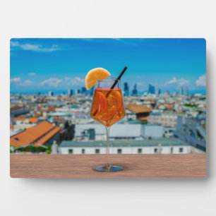 Spritz cocktail on a table with view of Milan Plaque