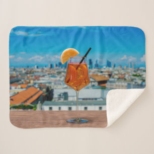 Spritz cocktail on a table with view of Milan Sherpa Blanket