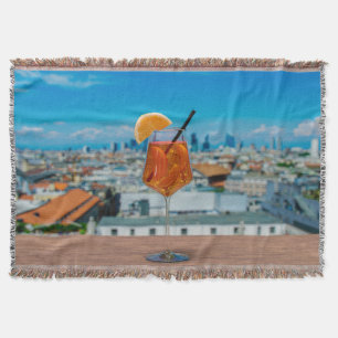 Spritz cocktail on a table with view of Milan Throw Blanket