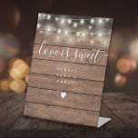 String Lights Rustic Wood Love Is Sweet Favour  Pedestal Sign<br><div class="desc">Featuring pretty string lights on a rustic wood background,  this elegant script love is sweet favour sign is perfect for all celebrations. Designed by Thisisnotme©</div>