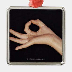 Studio shot of hand gesturing a sign metal tree decoration