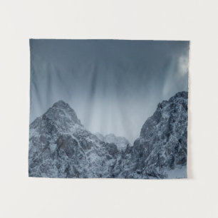 Sunlight and dark clouds over snowy mountains tapestry
