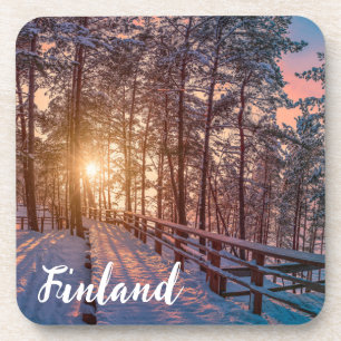 Sunset in snowy pine forest with sun ray coaster