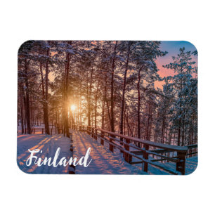 Sunset in snowy pine forest with sun ray magnet