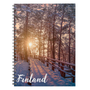 Sunset in snowy pine forest with sun ray notebook