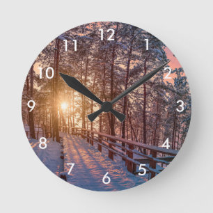 Sunset in snowy pine forest with sun ray round clock