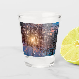 Sunset in snowy pine forest with sun ray shot glass