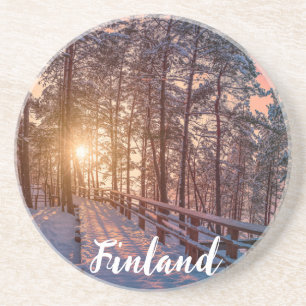 Sunset in snowy pineforest with sun ray coaster