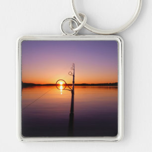 Sunset on a summer lake seen through a fishing rod key ring