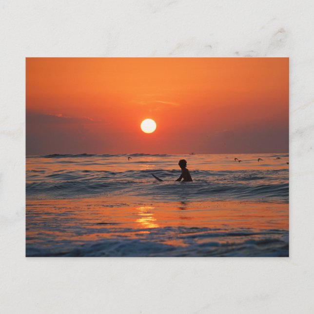 Sunset over the ocean with a surfer in the water postcard (Front)