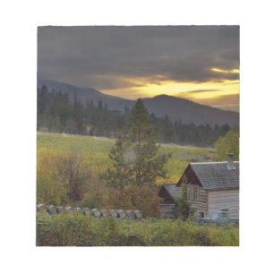 Sunset sky over vineyards and historic log cabin notepad