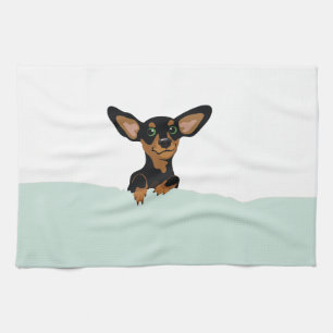 Supercute dachshund puppy under green duvet tea towel