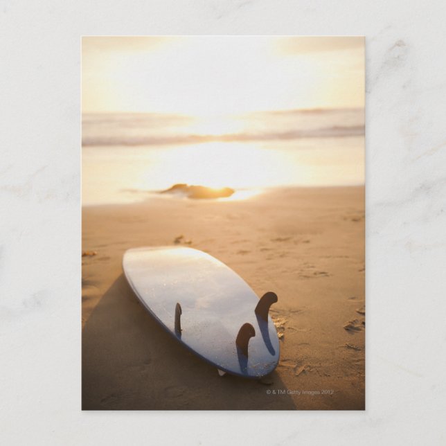 Surfboard laying on beach at sunset postcard (Front)