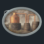 Swamp Moonshine Still Belt Buckle<br><div class="desc">A copper pot still churns away in a misty swamp. Dark smoke billows from the furnace while moonshine trickles into a jug from the worm. It looks like the moonshiner has run off though. Once should never leave a still alone when distilling. Actually, this would not be a particularly practical...</div>