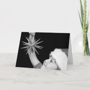 sweet girl in christmas hat and dress holding star holiday card