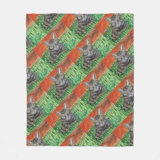 Tabby cat looking curious in grass fleece blanket 