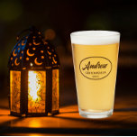 Taupe Stylised Wedding Groomsman Name Glass<br><div class="desc">Beer glass for the wedding groomsman that features his name printed in a taupe colour, stylised script inside a taupe colour oval border along with wedding date. A great party supply idea for a bachelor party! Personalise your beer glass by editing and replacing name and date with your own. Available...</div>