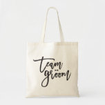 Team Groom Bow Tie Bachelor Party Wedding Bag<br><div class="desc">This design features a modern and bold black 'team groom' brushed calligraphy script with a stylish bow tie accent on a classic ivory white background. The background colour can be changed to any colour of your choice. You can easily add more text / info / details and/or photos to this...</div>