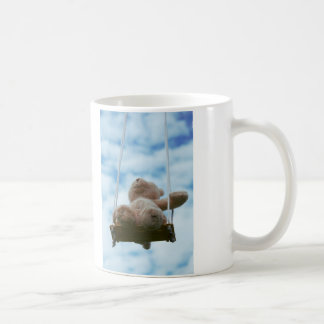 Teddy bear on a swing with a cloudy blue sky. coffee mug