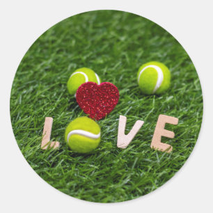 Tennis ball with love on green grass classic round sticker