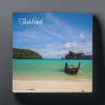 Thailand Beach Photo with Fishing Boat Plaque<br><div class="desc">An exotic travel destination. Thailand in South East Asia. This travel photo features a pretty scenic tropical beach from Thailand. Crystal clear turquoise waters, soft sandy beach, bright blue sky and lush green trees in the background. A single fishing boat sits on the beach ready to go fishing for the...</div>