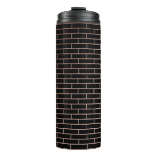The dark black brick wall has a rough surface as a thermal tumbler