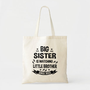 The little sister takes care of the big brother in tote bag
