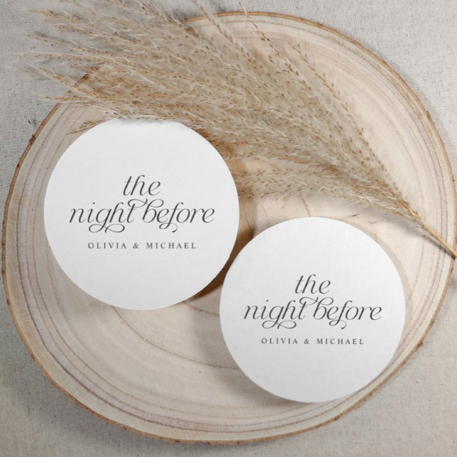 The Night Before Elegant Wedding Rehearsal Dinner Round Paper Coaster (Round black and white rehearsal dinner coasters with elegant script, styled on rustic wood.)